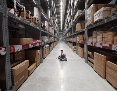 person sitting on shop floor in aisle in warehouse | inventory optimization | DemandCaster