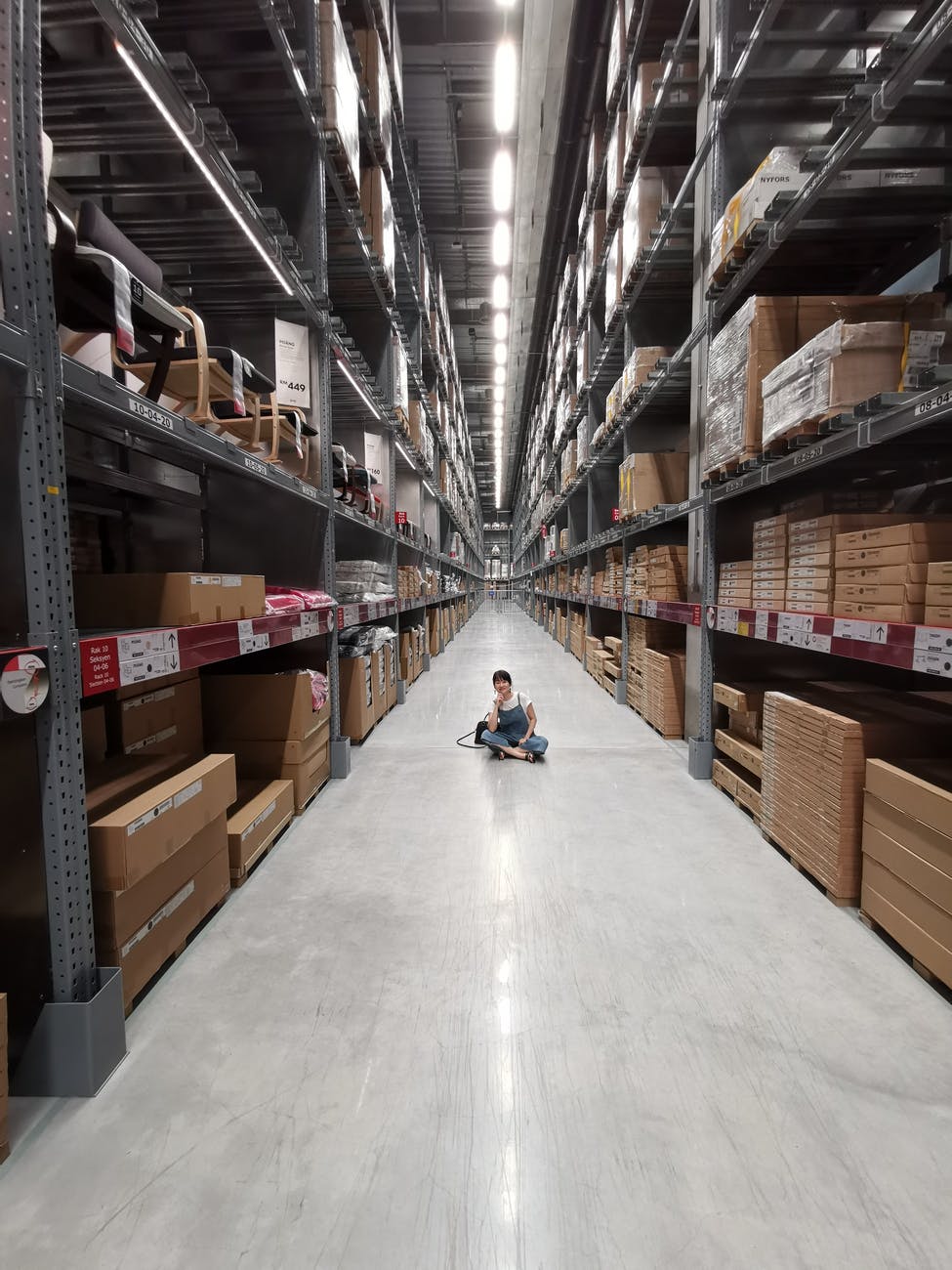 person sitting on shop floor in aisle in warehouse | inventory optimization | DemandCaster